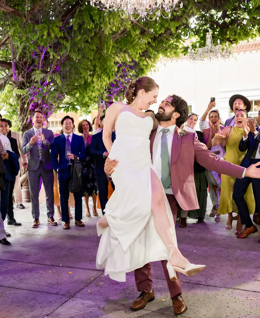 A couple celebrating on a full dance floor surrounded by their guests