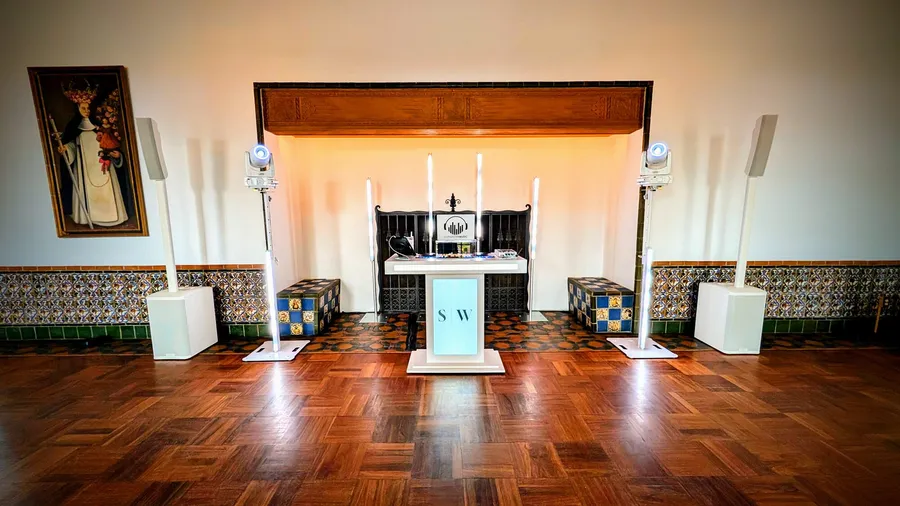 A Cutmaster Music DJ setup in the tiled fireplace nook at Los Poblanos, with candle-style uplighting and matching white speaker towers