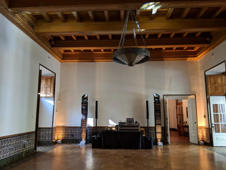 A high-ceilinged reception room at Los Poblanos, with wood-beamed ceilings and a wrought-iron chandelier over the dance floor